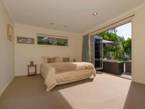 a bedroom with a bed and a large window at Cooks Getaway - Cooks Beach Holiday Home in Cooks Beach