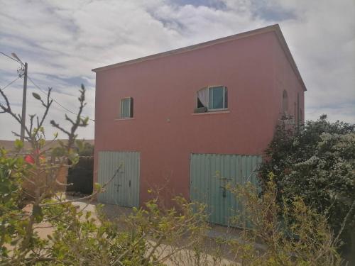 a red building with two windows and a fence at ferme jnane erroumane-settat in Settat