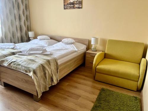 a bedroom with a bed and a yellow chair at Hotel Pelikán in Lučenec