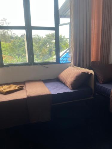 a bed sitting in a room with two windows at Night manner hostel in Ella