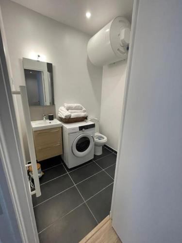 une salle de bain avec une machine à laver et un lavabo dans l'établissement 2P Porte de Paris, sortie métro face au bois, à Charenton-le-Pont