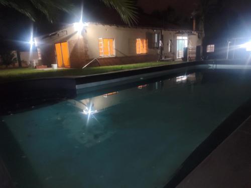 a swimming pool at night with a house at sunnyday in Johannesburg