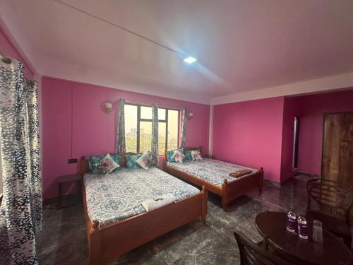 two beds in a room with pink walls at Odyssey Stays Nongrim, Cherrapunji in Cherrapunji