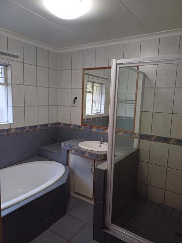 a bathroom with a tub and a sink and a bath tub at Willow Guest house in Vereeniging