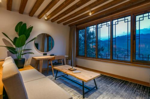 a living room with a couch and a table and windows at Xijiang Sanchunli Zhong Panorama Meisu in Xijiang
