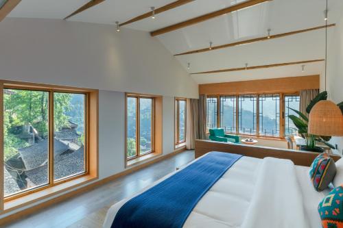a bedroom with a large bed and large windows at Xijiang Sanchunli Zhong Panorama Meisu in Xijiang