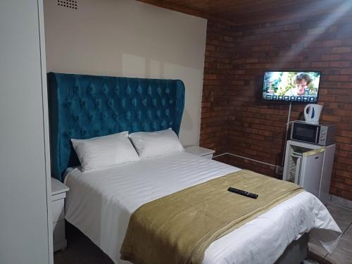 a bedroom with a bed with a blue headboard and a tv at Willow Guest house in Vereeniging
