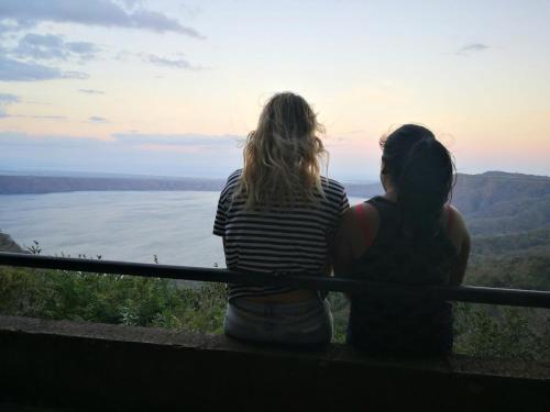 two girls sitting on a railing looking out over the water at La Casa de Leo - Hostal, Restaurante y Artesania local in San Juan de Oriente