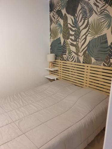 - une chambre avec un lit et un mur orné de plantes dans l'établissement La petite maison, à Aunac