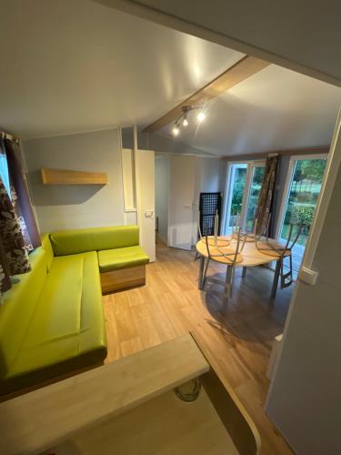 un salon avec un canapé vert et une table dans l'établissement Camping les Portes du Perche, à Mamers