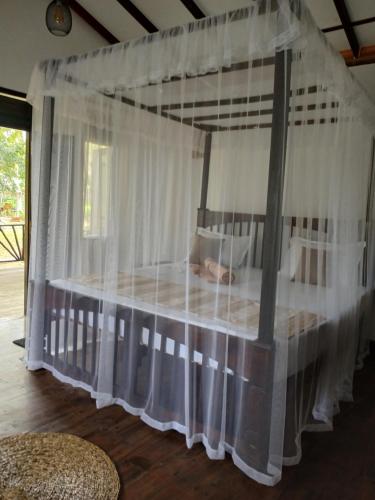 un letto a baldacchino con tende bianche in una stanza di Ginger Harmony Guesthouse and Cafe a Tangalle