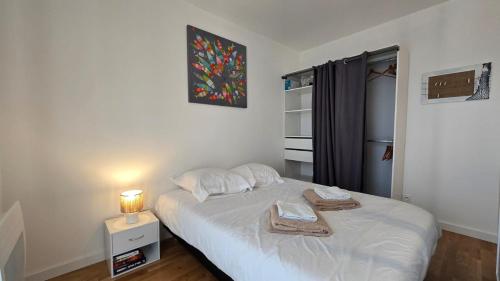 a bedroom with a bed with a lamp and towels on it at Vacances Ô Kastel - Studio Centre Ville proche de la mer in Fouesnant