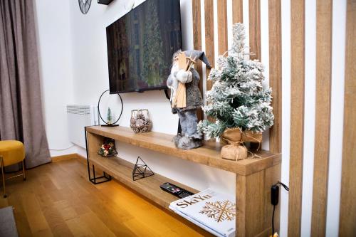 a living room with a christmas tree on a shelf at Apartman K&N - Jahorinska Vila in Jahorina
