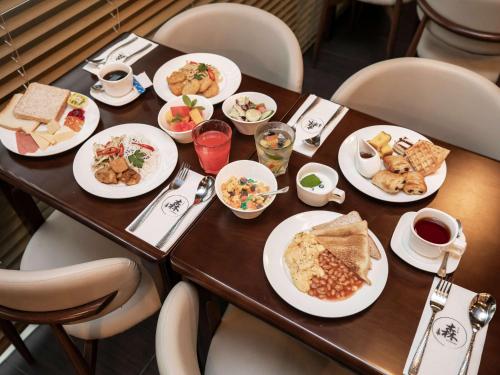 a wooden table with plates of food on it at ibis budget Singapore Imperial in Singapore