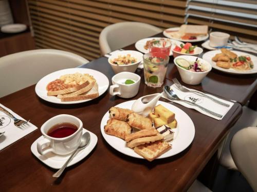 a table with plates of food and cups of coffee at ibis budget Singapore Imperial in Singapore