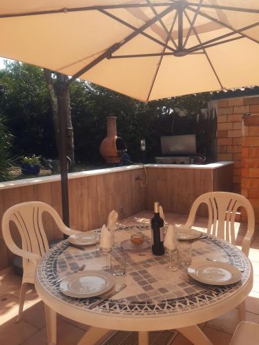 - une table et des chaises sous un parasol sur la terrasse dans l'établissement Villa familiale typique à Lacanau-Océan, à Lacanau
