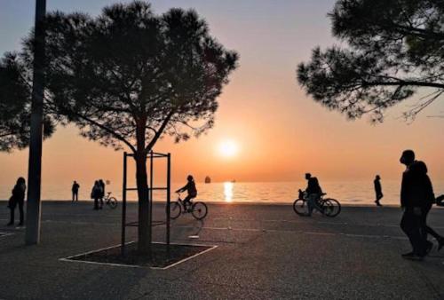 Eine Gruppe von Menschen, die bei Sonnenuntergang am Strand Fahrrad fahren. in der Unterkunft fruit tower in Thessaloniki