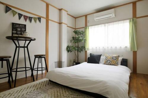 a bedroom with a white bed and a window at Nakamichi House 中道戸建 in Osaka