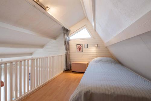 a attic bedroom with a bed and a window at Groenendijk Verhuur Vakantiewoning de Haerde 52 in Ellemeet in Ellemeet