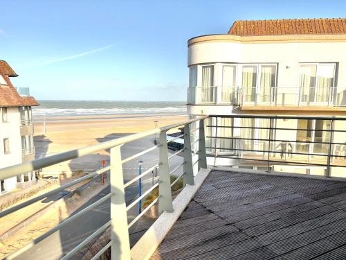 a balcony with a view of the beach and a building at Windjammer A3 - Sea View in Koksijde