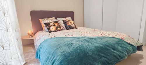 a bed with a green comforter and pillows at ENTRE GUILLEMETS, Terrasse privée, 2 chambres, Parking privé, proche de Paris in Brétigny-sur-Orge
