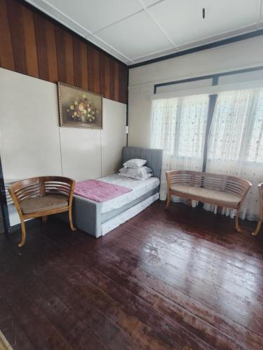 a bedroom with a bed and two chairs in it at Rizkie homestay in Tanah Rata