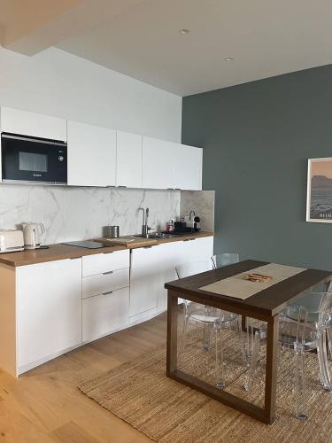 une cuisine avec des armoires blanches et une table en bois dans l'établissement Saint Jean de Luz, APPT 2 pièces équipé pour 4 pers, terrasse, vue océan, à Sainte-Barbe