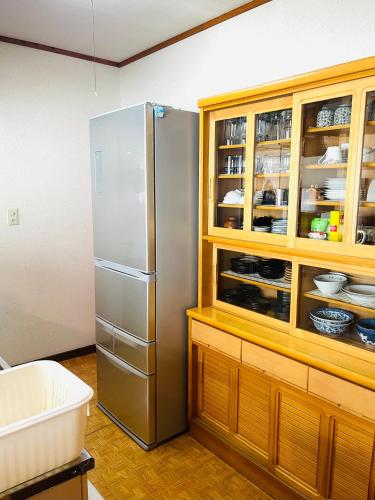 a kitchen with a stainless steel refrigerator and a wooden cabinet at 民泊JOYFUL天然温泉付きログハウス in Shiraoi