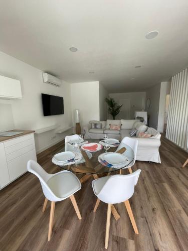 a living room with a table and white chairs at Apartamento Tronqueiras in Praia da Vitória