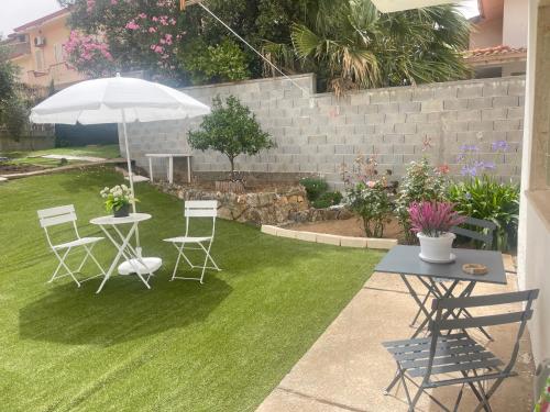 a patio with a table and chairs and an umbrella at Villa Eden in Domusnovas