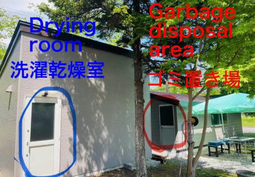 a house with a garagediscussed area and a tree at 民泊JOYFUL天然温泉付きログハウス in Shiraoi