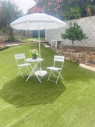 a table and chairs with an umbrella on a lawn at Villa Eden in Domusnovas