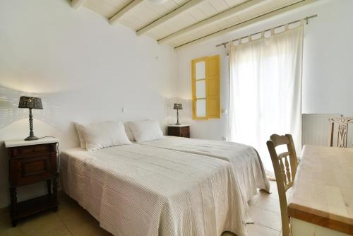 a white bedroom with a bed and a window at Akrotiraki Villas in Tinos Town