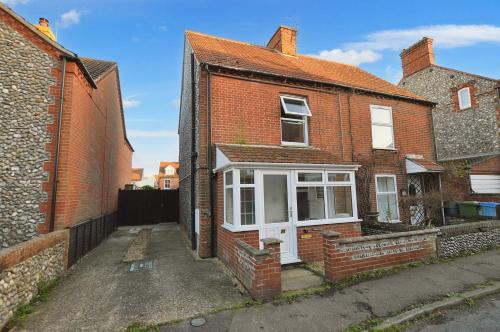 a red brick house with a white window at Philips Cottage in Sheringham