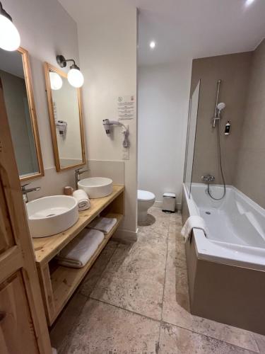 a bathroom with two sinks and a tub and a toilet at Moulin de la Roque in Althen-des-Paluds