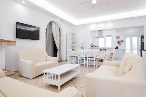 a living room with white furniture and a table at Villa Christelle Luxury Pescoluse by HDSalento in Marina di Pescoluse