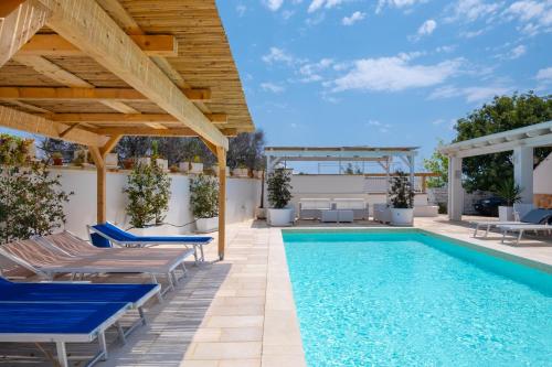 a pool with blue chairs and a wooden pergola at Villa Christelle Luxury Pescoluse by HDSalento in Marina di Pescoluse