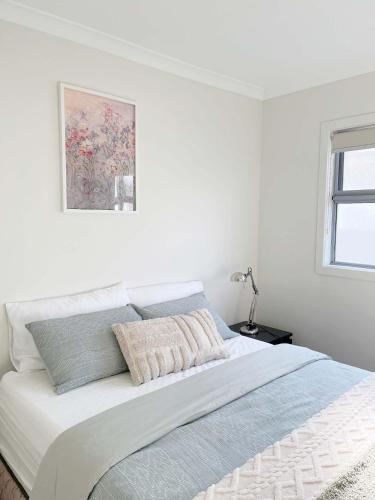 a white bedroom with a large bed with a picture on the wall at Special offer! Jap-inspired stay with Lakeside view Room OR Entire House in Berwick