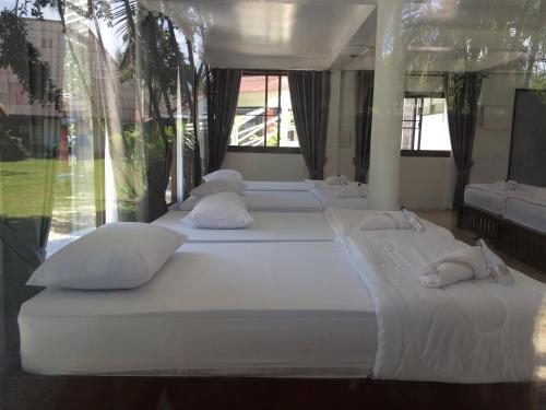 a row of white beds in a room with windows at LayTrang Pakmeng Marina Spa and Resort in Trang