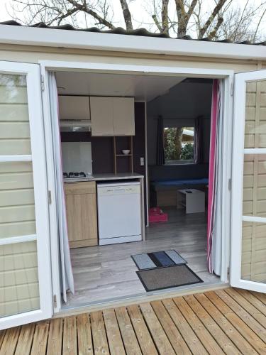 une cuisine avec une porte s'ouvrant sur une terrasse. dans l'établissement Mobilhome 2 chambres climatisé camping 3 étoiles, à Saint-Georges-de-Didonne