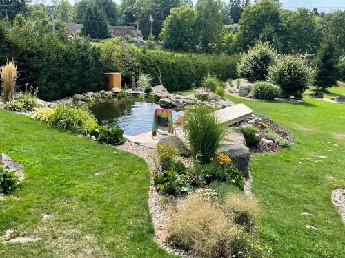 a garden with a pond with a chair in it at Log cabins at Iron Rose in Czech Canada in Nová Bystřice