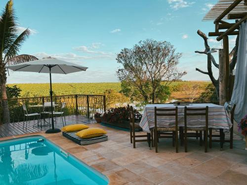 a patio with a table and chairs next to a pool at Glamping do luxo - Tenda Curicaca in Delfinópolis