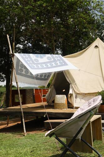 a tent and a chair in front of a table at Glamping do luxo - Tenda Curicaca in Delfinópolis