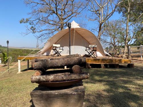 a yurt with a table and logs in front of it at Glamping do luxo - Tenda Curicaca in Delfinópolis