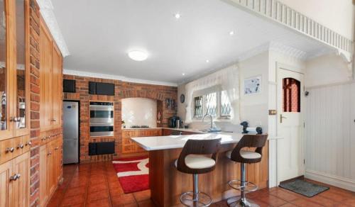 cocina con armarios de madera y barra con taburetes en Federation Style 4 bedroom House with Ocean View, en Lakes Entrance