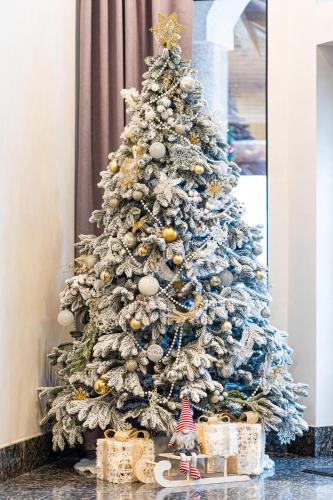 a blue christmas tree with presents under it at Premium hotel & SPA in Bukovel