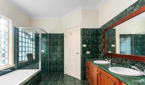 Un baño con dos lavabos, una bañera y un espejo. en Federation Style 4 bedroom House with Ocean View, en Lakes Entrance