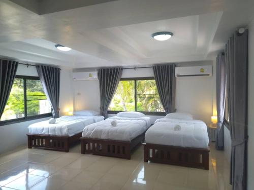 a bedroom with three beds in a room with windows at LayTrang Pakmeng Marina Spa and Resort in Trang