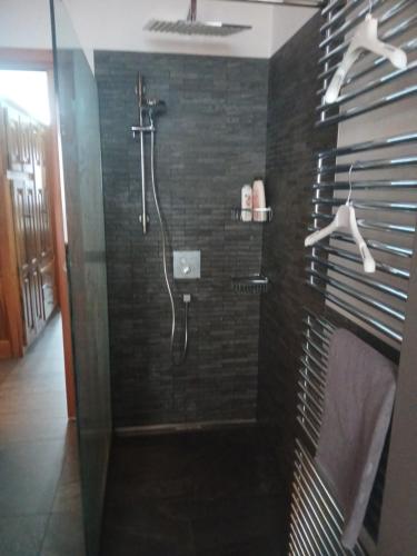 a bathroom with a shower with black tiles at La mansarda del cervo in Santa Maria Maggiore