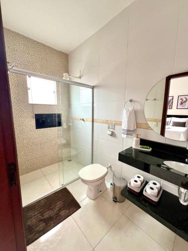 a bathroom with a shower and a toilet and a sink at Pousada Aconchego De São Thomé in São Thomé das Letras